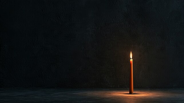 Deep charcoal plaster creates a minimal Halloween background with a single slender orange candle positioned off-center, a faint pool of warm illumination, subtle wall texture