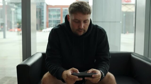 Detailed shot of human hands using a mobile phone in landscape orientation, typing, watching a video, or playing an online game indoors. 