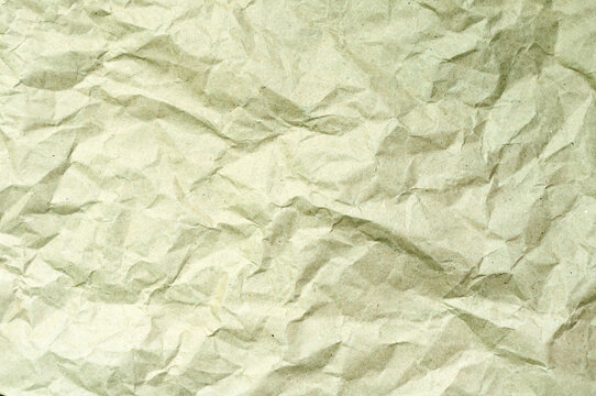 Texture background of crumpled pale green paper with soft folds and subtle wrinkled surfaces