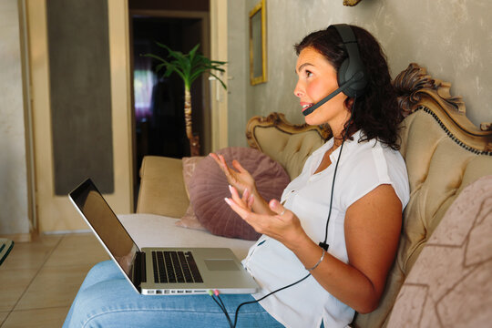 Woman speaking during online meeting with laptop at home