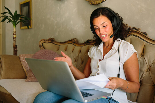 Smiling woman reviewing documents while working on laptop