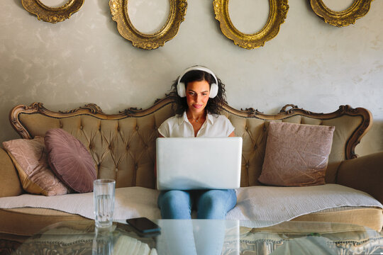 Woman working remotely on laptop with headphones at home