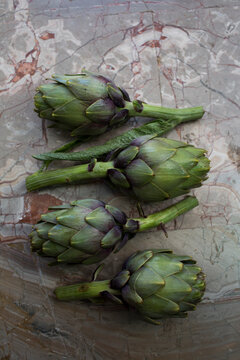 Fresh Green Globe Artichokes on Marble Stone Surface Top Down View