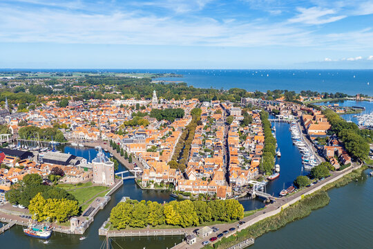 Aerial view of the historic town with its characteristic orange-tiled rooftops, canals, and harbor surrounded by lush greenery in Enkhuizen, North Holland, Netherlands.