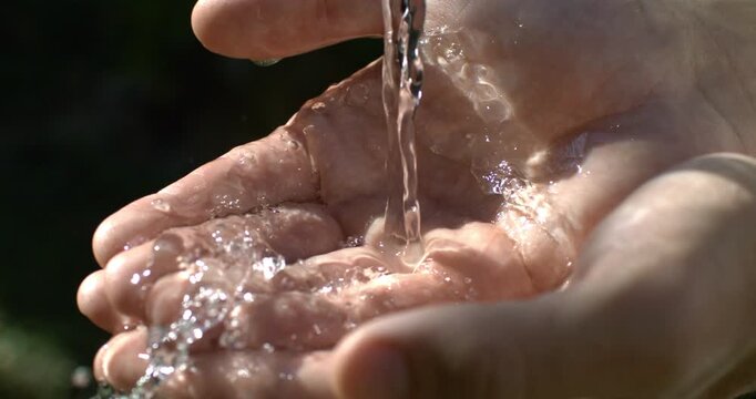 Both hands gently joined as water flows over them, creating a cinematic symbol of unity, healing, acceptance and renewal. Slow motion captures the intimate connection between hands and water.