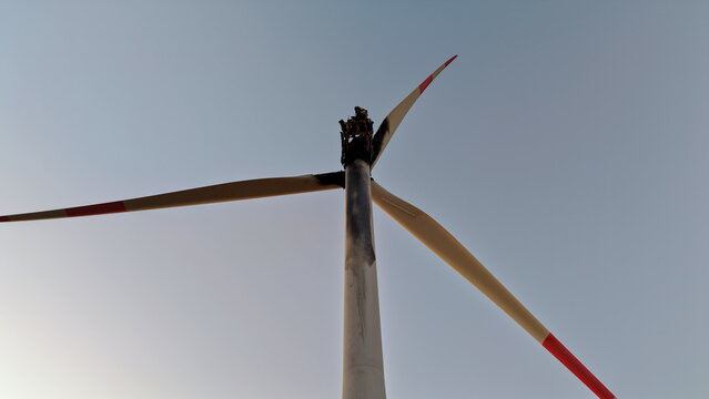 Aerial view of a damaged wind turbine with a scorched nacelle and blades against a clear sky in Vladimirovac, Vojvodina, Serbia.