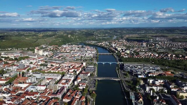 Aerial view of Maribor, Slovenia, along the Drava River, featuring the historic Old Bridge, multiple bridges, urban architecture, green hills and surrounding countryside.
