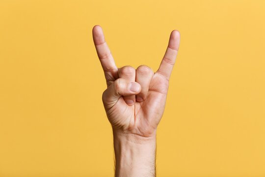 The Rock On Hand Gesture Against Bright Yellow Studio Background