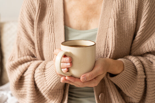 Woman holding warm coffee mug enjoying cozy moment