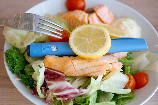 ozempic semaglutide injection pen salmon salad healthy meal weight loss diabetes medication lemon fork plate concept of healthy lifestyle nutrition medical treatment