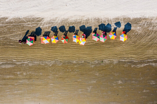 Aerial view of colorful beach umbrellas lined up on the sandy shore of Kuakata beach in Kuakata, Barisal Division, Bangladesh.