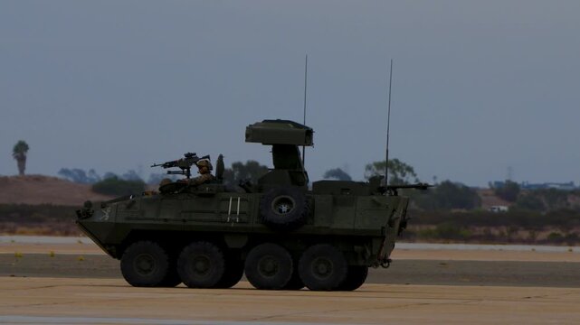 Green armored tank vehicle with 8 wheels driving during a military exercise