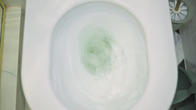 Water swirls in a toilet bowl as it moves through a flushing cycle. The sequence shows the water level decreasing and the inner workings of the toilet's flushing mechanism