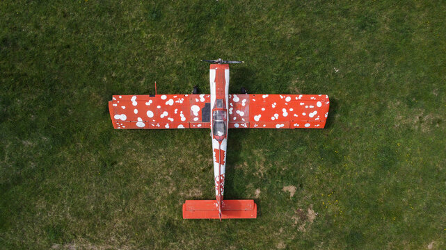 Serbia - 11 April 2021: Aerial view of a small airplane with a distinctive red and white polka-dot pattern parked on a green grassy field.