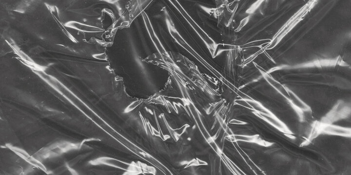 Crumpled plastic wrap texture with torn hole, transparent cellophane film overlay on black background, wrinkled polyethylene sheet