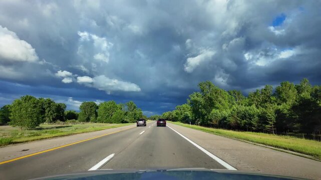 Driving on Interstate 96 freeway in Michigan under a dramatic stormy sky