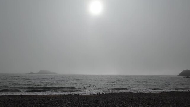 Seascape moods mystical light island in sea for gentle waves breaking on shingle beach Copper Coast Waterford Ireland