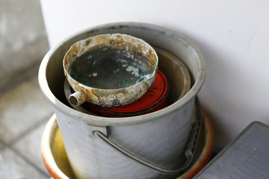 Old rusty kitchenware stored in plastic bucket.