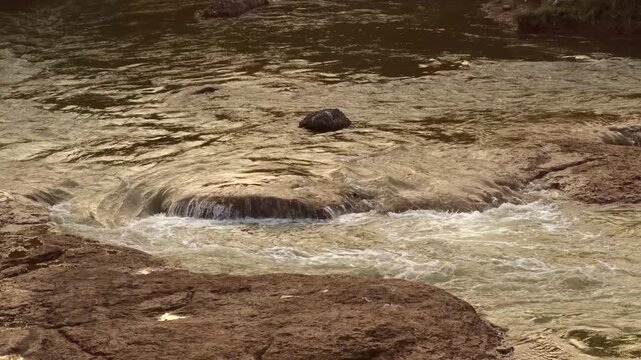 Brown River Water Flowing Over Rocky Cascades and Rapid Swirls in Close Up Stock Footage Stream Current Texture and Background