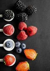 Fresh mixed berries on white spoons over dark background with space for text © Наталья Бабак