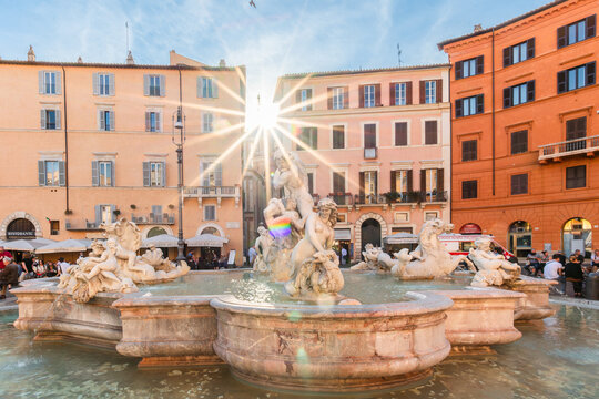 View of the Fountain of the Four Rivers in Piazza Navona with a sunburst effect behind historic buildings in Rome, Lazio, Italy.