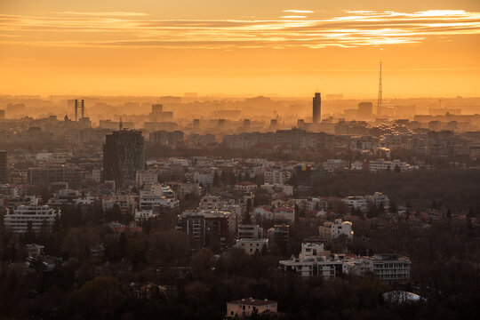 View of the Bucharest skyline bathed in the warm golden light of sunset with hazy atmosphere over the urban buildings in Bucharest, Bucharest, Romania.