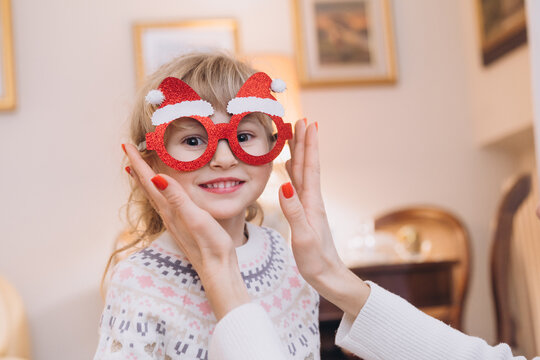 Mom tries on funny New Year's glasses for a little girl