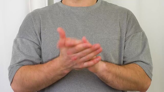 A young man claps his hands vigorously and without stopping. A man applauding against a white background.