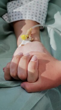 Young girl holds mother hand during quiet hospital recovery