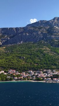 Brela, Croatia, aerial view of the coastal town with Biokovo mountain range in the background, blue sea and pine forest