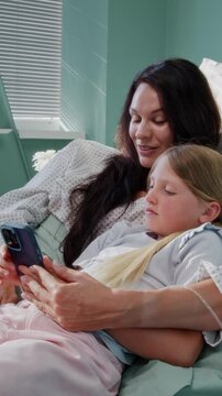Mother and daughter share smartphone during hospital recovery