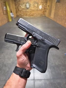 BALTIC STATES - SEPTEMBER 29, 2026: Shooter holding modern Glock 17 and 19 Gen 6 handguns in hands inside an indoor shooting range practice facility.