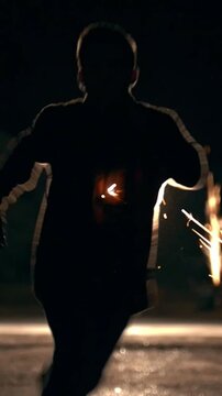 Young man run away through the sparks from grinder at night