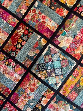 Close-up of a vibrant handmade Japanese-inspired patchwork quilt with colorful floral motifs and traditional white sashiko stitching