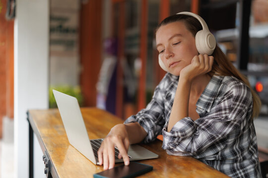 Female traveling in the cities in Chiang Mai Female digital nomad relaxing with headphones and laptop in an outdoor cafe in Chiang Mai, Thailand