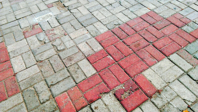 Damaged red and gray interlocking paving block sidewalk.