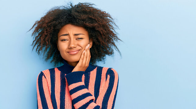 Young woman with afro hairstyle touching her cheek feeling toothache