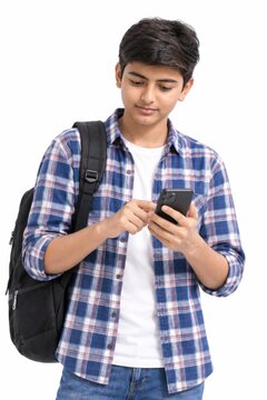 young indian college boy holding backpack and using smartphone on white background