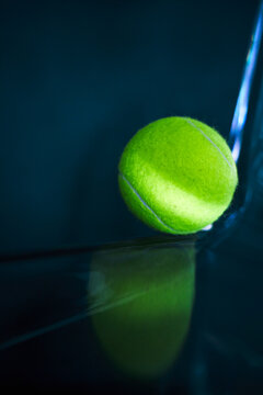 Neon tennis ball on a dark glossy surface.