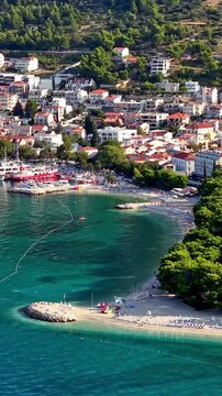 Croatia, aerial view of the coast, beach, and town of Tucepi along the Adriatic Sea with turquoise water, pine trees, and boats