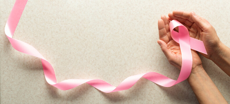 Pink Ribbon Held in Hands for Breast Cancer Awareness