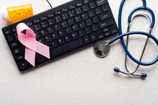 Breast Cancer Awareness Ribbon with Stethoscope and Pills on Keyboard
