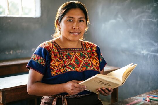 Una mujer maya guatemalteca, con un huipil tradicional colorido, sosteniendo un libro frente a una pizarra