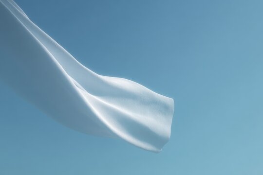 A white cloth flying in the air against a bright blue sky. the cloth is smooth and silky and the sky is a deep clear blue.