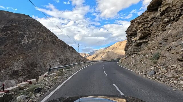 POV video of a vehicle drives through a dark rocky gorge with golden sand-colored mountains visible - Spiti Valley Himachal Pradesh India | Himalayan road trip GoPro dashcam 4K