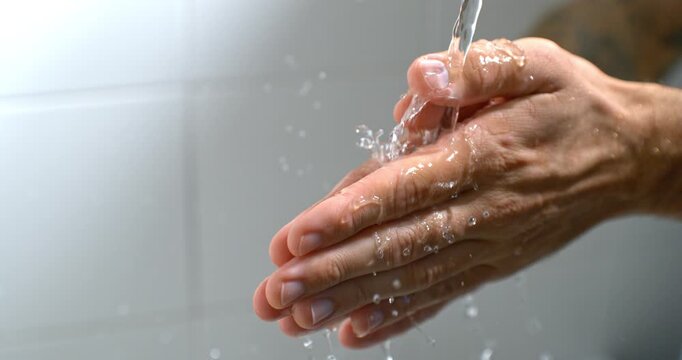 Hands being washed under flowing water in slow motion, creating a cinematic image of cleansing, renewal and letting go. Natural droplets and movement evoke purity, care and emotional relief.
