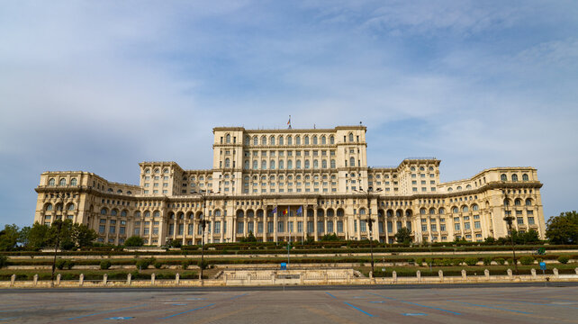 View of the massive neoclassical Palace of the Parliament building, featuring grand architecture, a symmetrical facade, and manicured green terraces in Bucharest, Bucharest, Romania.