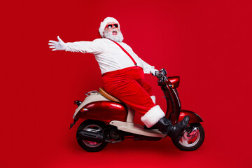 Obraz premium Santa Claus on a red scooter celebrating Christmas with joy and festive style against a bold red background