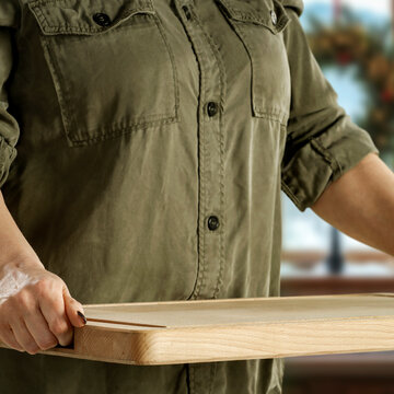 Woman holding wooden tray with copy space &ndash; cozy winter interior concept.