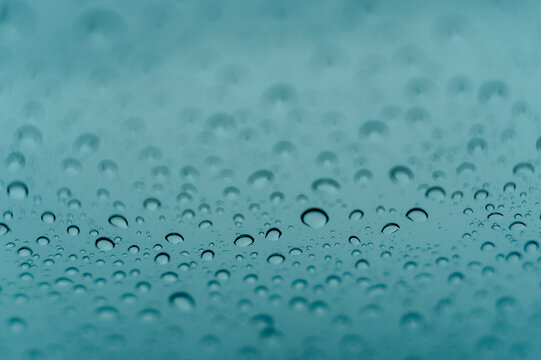 View of water droplets on a glass surface with a soft blue background, Iceland.
